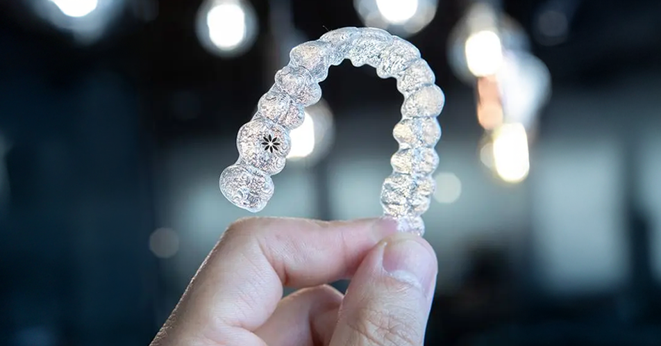 Imagem de mão segurando um alinhador invisível Invisalign®.