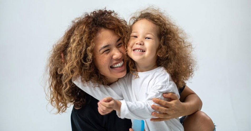 Criança e mãe sorriem felizes.